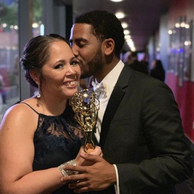 Jharrel is kissing his mom on her cheek while holding the Emmy award.